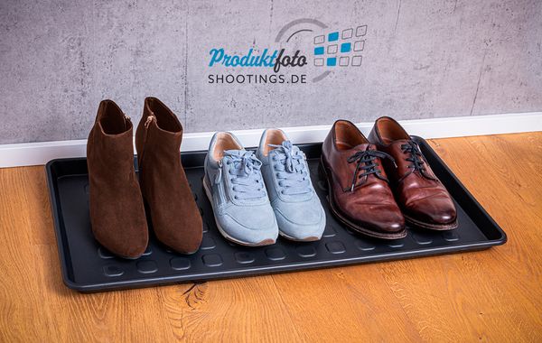 Produktfotografie on Location von einer Kunststoff Schuhwanne mit 3 paar Schuhen auf Parkettfußboden und Betonhintergrund
